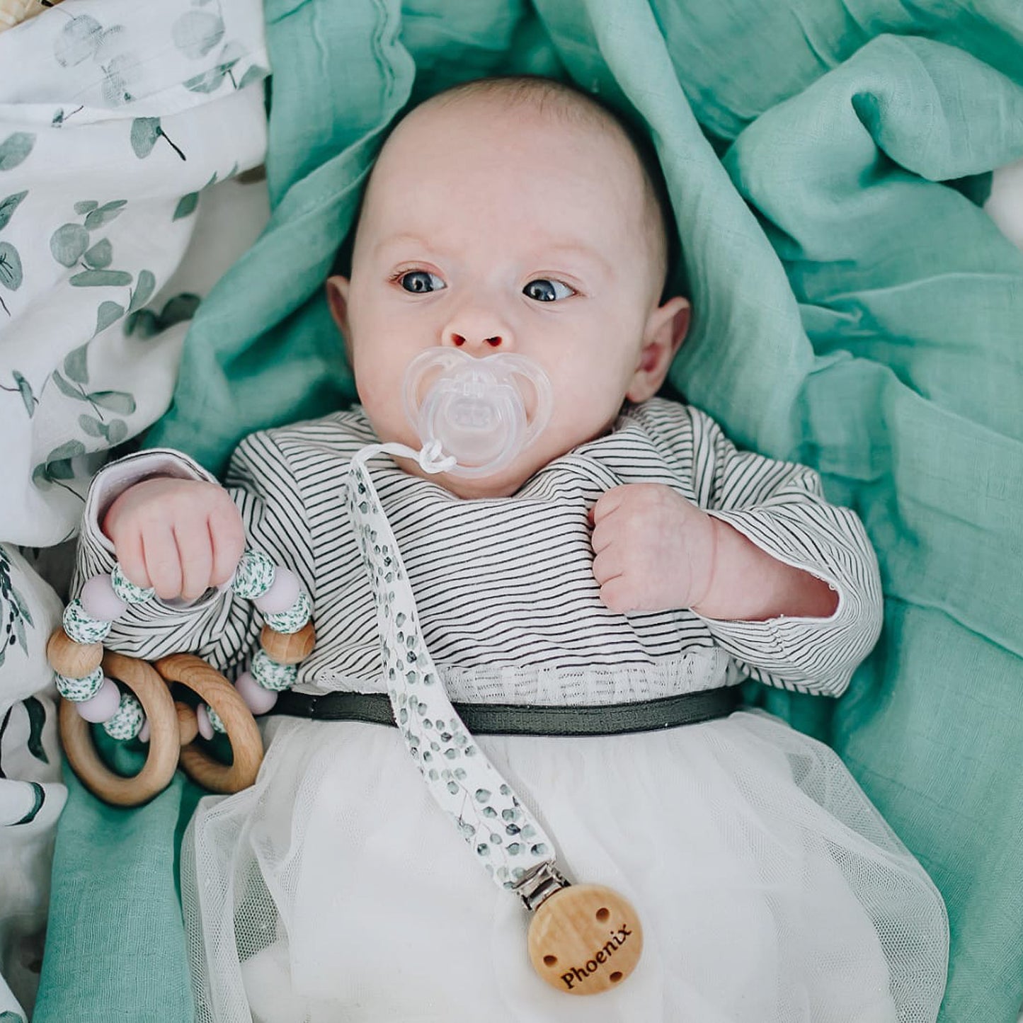 baby with fabric dummy clip In leaf print and teething toy